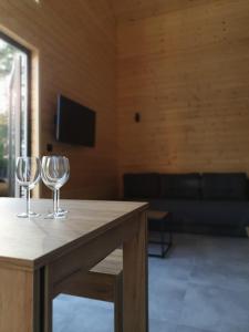 two wine glasses sitting on a wooden table in a room at Piaski Rogowa in Rogowo