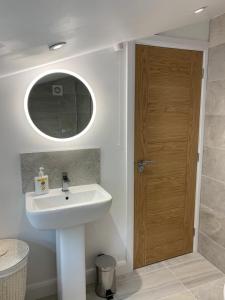 a bathroom with a sink and a wooden door at CAERNARFON Quality Townhouse in Caernarfon