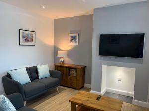 sala de estar con sofá y TV de pantalla plana en CAERNARFON Quality Townhouse en Caernarfon