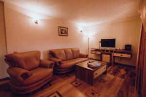 a living room with two chairs and a television at Denisa Boutique in Poiana Brasov