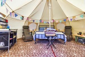 Pitch Perfect Glamping Norfolk في Little Hautbois: خيمة بسرير وكراسي في الغرفة