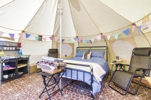 Pitch Perfect Glamping Norfolk في Little Hautbois: غرفة نوم بسرير في خيمة