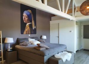 a bedroom with a bed with a painting of a woman at B&B Drenthe in Westerbork