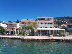a building on the water next to a body of water at Apartments Antonio in Tisno