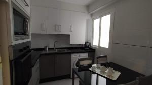 una cocina con armarios blancos y una mesa con sillas. en Apartamento Aliste, en Nerja