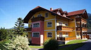 een groot geel en rood huis met een tuin bij Appartementhaus Eberlhof in Pruggern