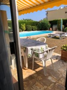 een tafel en stoelen op een patio naast een zwembad bij Villa C3 Arthur Rimbaub chambre d’hôte piscine proche mer plage 600m in Cagnes-sur-Mer
