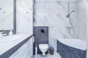biała łazienka z umywalką, toaletą i wanną w obiekcie INPOINT CRACOW Mogilska Tower Apartments near Tauron Arena w Krakowie