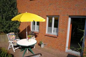 a table with a yellow umbrella next to a brick building at Ferienwohnung in Schleswig-Holstein, Hohn in Hohn