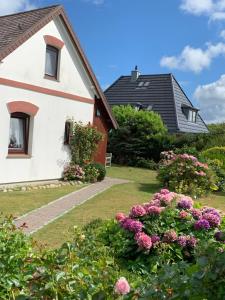 a white house with flowers in the yard at Haus Boy Jensen Wohnung Sonnenplatz in Wenningstedt