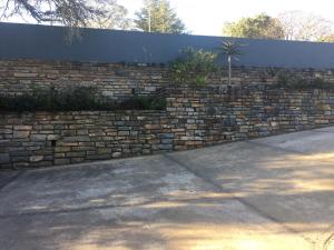 a brick retaining wall with a fence and a sidewalk at Wedmore Place in Grahamstown