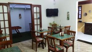 a dining room with tables and chairs and a tv at Pousada Cavalo Branco in Cabo Frio