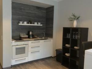 eine Küche mit weißen Schränken und einem schwarzen Regal in der Unterkunft Engels Hof in Wolfsburg