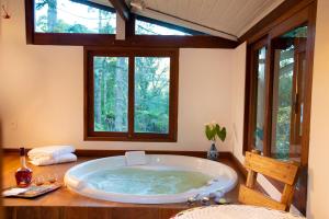 bañera grande en una habitación con ventanas en Pousada Casa Bonita en Visconde De Maua