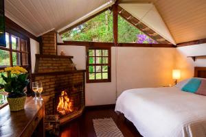 1 dormitorio con chimenea y 1 cama en una habitación en Pousada Casa Bonita en Visconde De Maua