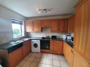 cocina con armarios de madera, lavadora y secadora en Waterfront View Apartment, en Carrick on Shannon