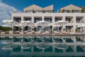 a hotel with a swimming pool with umbrellas at Vivid Blue Serenity Resort in Sveti Stefan