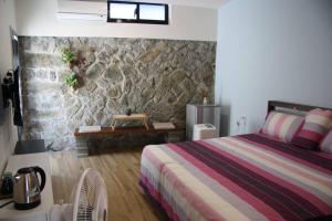 a bedroom with a bed and a stone wall at Jiufen Back Yard Homestay in Jiufen