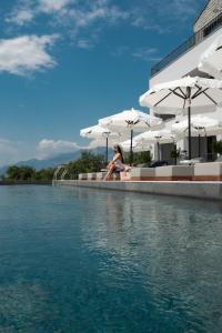 a woman sitting on the edge of a pool of water at Vivid Blue Serenity Resort in Sveti Stefan