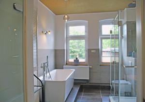 uma casa de banho com banheira e 2 janelas em Altstadt Ferienwohnung Erfurt em Erfurt