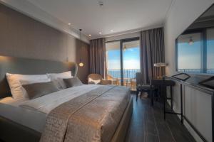 a hotel room with a large bed and a desk at Vivid Blue Serenity Resort in Sveti Stefan