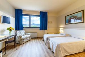 una habitación de hotel con 2 camas y una silla en Hotel Country Club, en Capannori