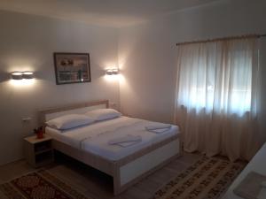 Schlafzimmer mit einem Bett mit weißer Bettwäsche und einem Fenster in der Unterkunft Apartments City Paradise in Mostar