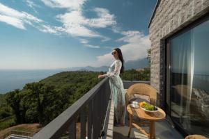 a woman standing on the balcony of a house at Vivid Blue Serenity Resort in Sveti Stefan