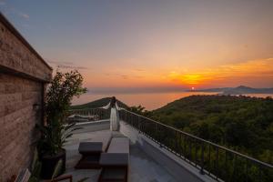 a woman standing on a balcony watching the sunset at Vivid Blue Serenity Resort in Sveti Stefan