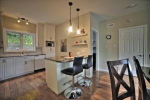 a kitchen with a counter and two bar stools at Chalet Potvin Bouchard in LʼAnse-Saint-Jean