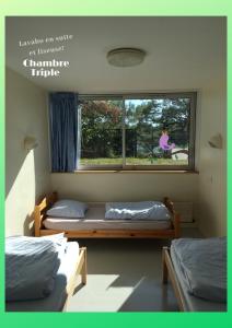 two beds in a room with a window at Auberge de Jeunesse HI Lorient in Lorient