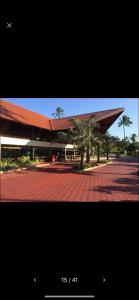 a building with a red roof and palm trees at Marulhos Resort Flat Vista Mar in Porto De Galinhas