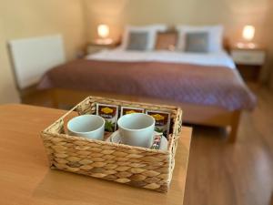 a basket filled with mugs on a table with a bed at Guest House Golja in Bled