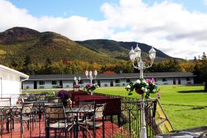 un groupe de tables et de chaises avec des montagnes en arrière-plan dans l'établissement Mountain View Motel & Cottages, à Pleasant Bay