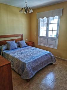 a bedroom with a bed with a blue comforter and a window at Apartamentos Brito 3 in Órzola