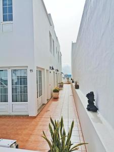 an empty courtyard of a white building with plants at Apartamentos Brito 3 in Órzola