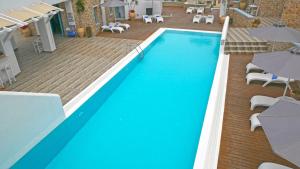 a swimming pool with chairs and umbrellas in a hotel at Nautilus Dome in Fira