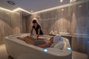 two women laying in a bath tub in a bathroom at Vivid Blue Serenity Resort in Sveti Stefan