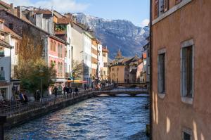 a river in a city with a bridge and mountains at Les Loges Annecy Vieille Ville in Annecy