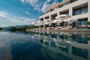 a pool of water with umbrellas and a building at Vivid Blue Serenity Resort in Sveti Stefan