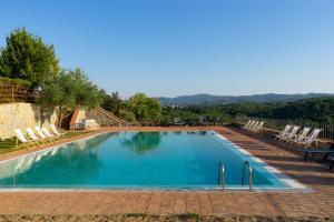 a large swimming pool with chairs and a table at Tenuta Toscanità in Cavriglia