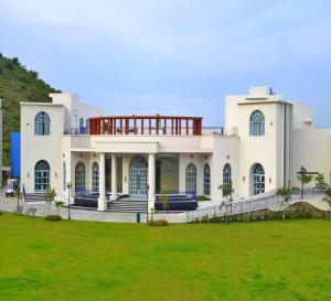 una gran casa blanca con césped verde en Ramee Royal Resorts & Spa - Udaipur, en Udaipur