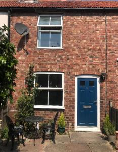 a brick house with a blue door and a table at Attractive 2 bed cottage in Hempton Fakenham in Fakenham