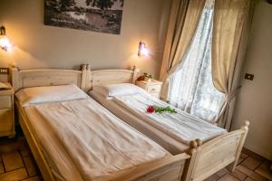 een slaapkamer met 2 bedden en een raam met rozen bij Agriturismo La Zangola in Tremosine Sul Garda