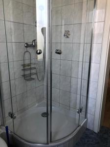 La salle de bains est pourvue d'une douche avec une porte en verre. dans l'établissement Haus Hoogelucht - Ferienwohnung, à Langeoog