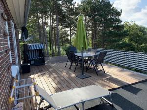 a deck with a table and chairs and a green umbrella at Haus Hoogelucht - Ferienwohnung in Langeoog