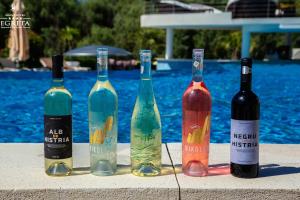 four wine bottles sitting on a table next to a pool at New Egreta Resort in Dunavăţu de Jos