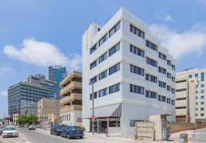 un edificio blanco alto en una calle de la ciudad con coches en Dave Downtown, a member of Brown Hotels en Tel Aviv