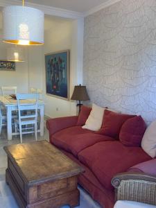 エステポナにあるHacienda Del Sol Apartmentのリビングルーム(赤いソファ、テーブル付)