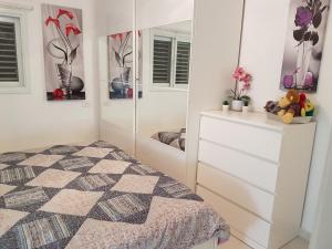 a bedroom with a dresser and a mirror at Blau Guesthouse in Netanya